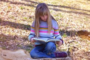Mädchen liest ein Buch in der Natur - Lesepicknick